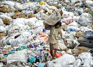 A worker carries a sack filled with used plastic items at a grinding plant near Srinagar.