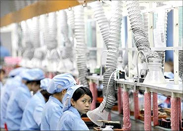 An employee looks up while working along a production line at Suzhou Etron Electronics factory.