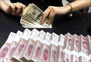 An employee counts US dollars next to yuan banknotes at a bank.