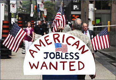 A man holds a sign reading American Jobless Wanted in Toronto.