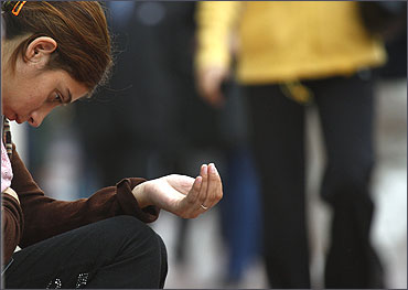 A beggar stretches out a hand as she sits on a central Athens street.