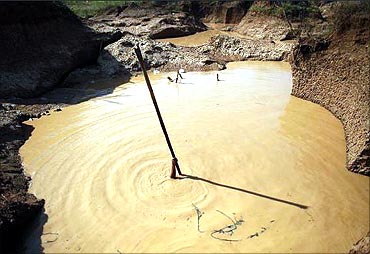 A man holds a stick as he installs a pump to extract mud at a primitive gold mine in Panompa.