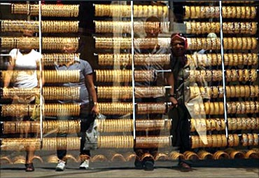 People are reflected on the window of a jewellery shop where gold bangles are on display in Istanbul
