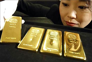 An employee poses with gold bars at the Ginza Tanaka store in Tokyo.