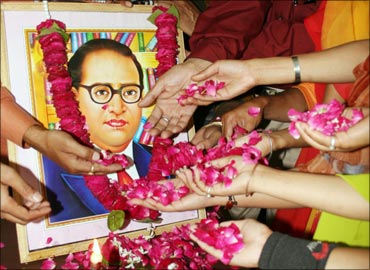 People scatter rose petals in front of a portrait of B R Ambedkar.
