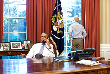 Vice President Joe Biden (R) looks out the window as U.S. President Barack Obama talks on the phone.