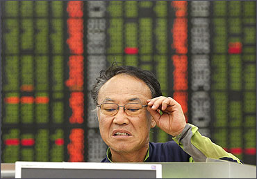 An investor reacts as he looks at a computer monitor showing stock prices.