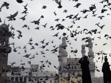 Pigeons fly against the backdrop of the historic Charminar monument.