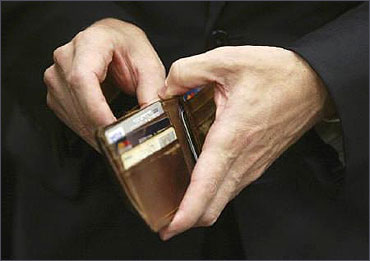 A man puts a piece of foreign currency back in his wallet.