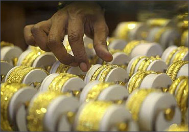 A store keeper arranges gold bangles.