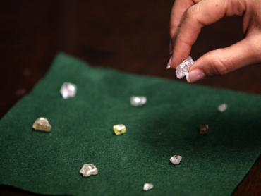 A visitor holds a 17 carat diamond at a Petra Diamonds mine in Cullinan.