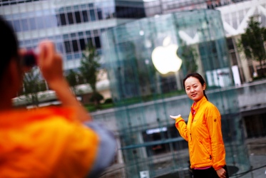 A woman poses in front of an Apple retail store at the financial district in Shanghai.