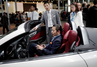 A potential costumer sits at a Mercedez Benz SLK 350 at the Shanghai Auto Show.