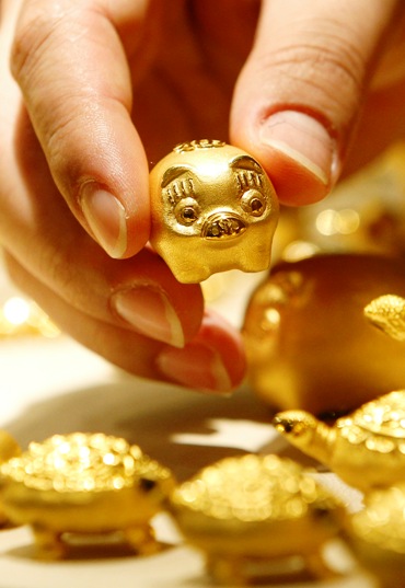 An employee of a jewellery shop holds a gold pig.