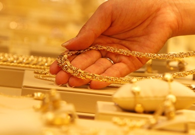 An employee displays a gold necklace during a photo opportunity at the Ginza Tanaka store in Tokyo.