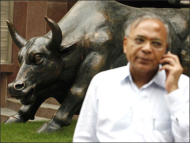 A man stands in front of a bull statue outside the BSE.