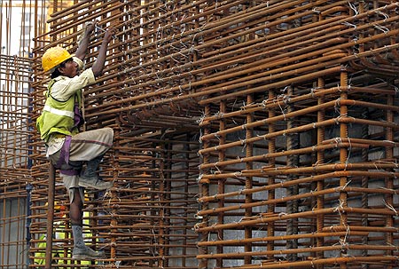 A worker climbs to fasten iron rods together at the construction site of a high-rise building in central Mumbai.