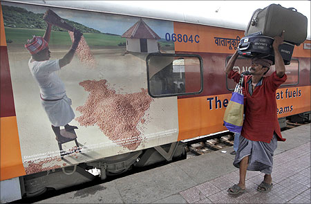 A porter carries luggage of a passenger at a railway station in Kolkata.