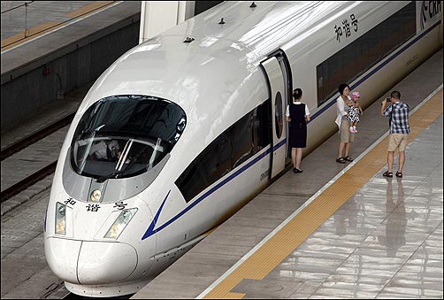 A passenger holding her child poses for a photo next to the lead car of a CRH380BL high-speed bullet train at Beijing.