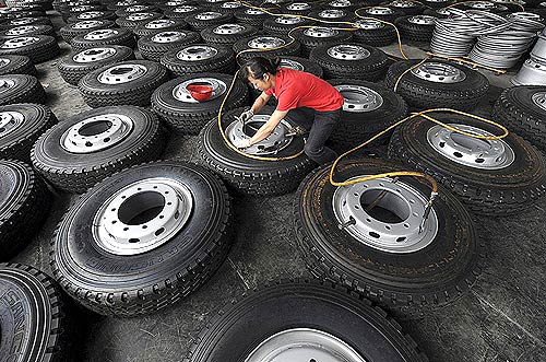 An employee inflates tyres at a wheel rims manufacturing factory.