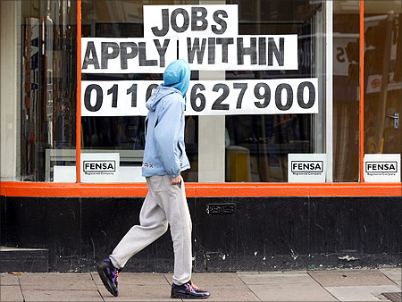 A man walks past a shop advertising job vacancies in Leicester, central England.