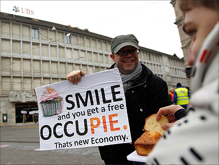 A demonstrator offers cakes as he attends Occupy Paradeplatz protest in front of Swiss banks UBS and Credit Suisse in Zurich.