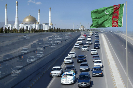 A wedding convoy passes Turkmen flag near mausoleum of the country's former leader Niyazov near Ashgabat.