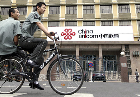 Security guards ride past a China Unicom office in Beijing.