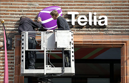 Workmen install a sign with TeliaSonera's new corporate logo.