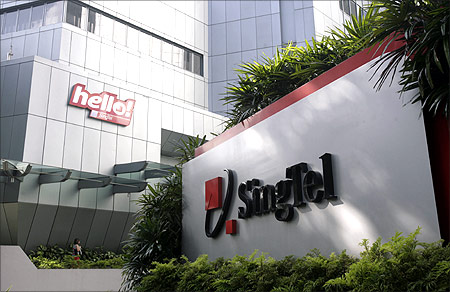 A customer walks past Singtel logos after visiting a Hello shop at the company's headquarters in Singapore.