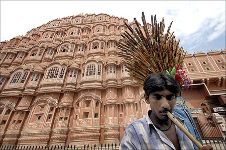 A vendor plays a flute as he tries to attract people to buy flutes in front of Hawa Mahal.
