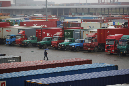 A man walks near trucks parked in a shipping container area at Shanghai Yangshan port, China.