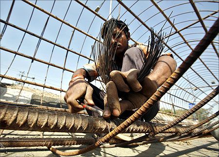 A labourer works on reinforcing bars at a construction site to build a bridge.