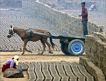 A man rides on a horse-drawn cart in a brick factory on a cold winter morning at Togga village.