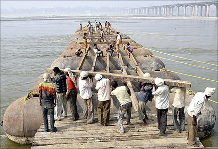 Labourers construct a temporary bridge made up of pontoons for Magh Mela festival on the river Ganges.