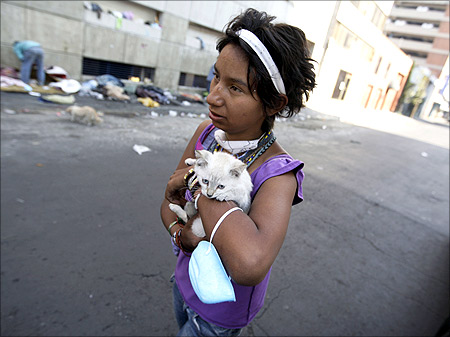 A homeless girl carries a kitten and a surgical mask after a routine check up for flu symptoms at a mobile clinic in downtown Mexico.