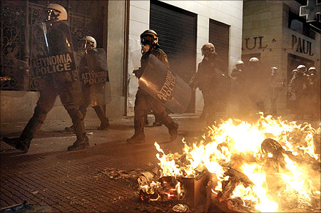 Riot policemen walk past burning garbage during riots around Syntagma (Constitution) Square in Athens.