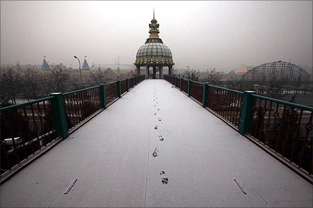 Footsteps in fresh snow are seen across a walkway.