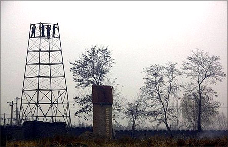 Farmers dismantle a tower in a field.