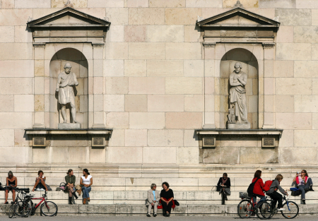 People enjoy the sunny weather sitting on the stairs in front of Munich's Glyptothek museum.