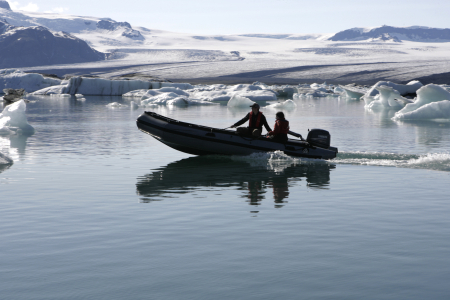 People travel in a boat as they pass blocks of ice from Breidamerkurjokull's Vatnajokull glacier in Iceland.
