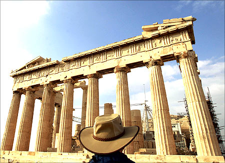 A tourist stands in front of the Parthenon Temple at the archaeological site of the Acropolis Hill in Athens.