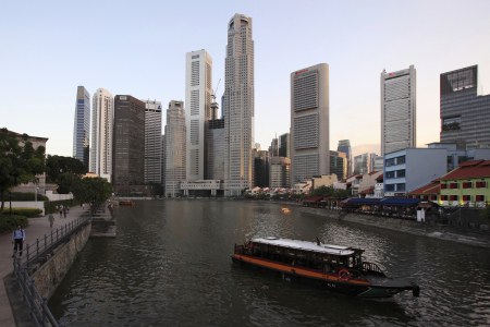 A tour boat travels up Singapore River past the skyscrapers of the financial district.