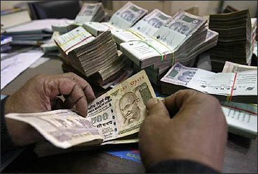 A bank employee counts rupee notes.