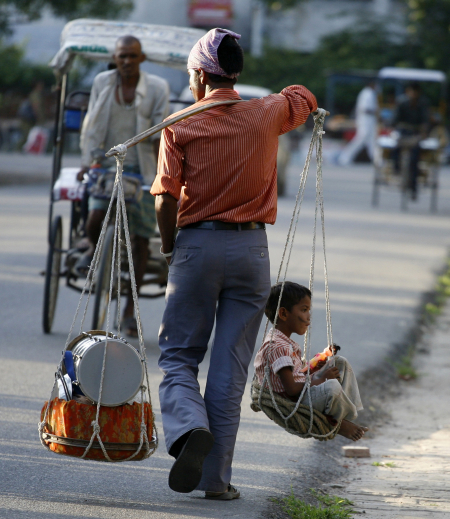 A street performer carries a child after a show in Noida.