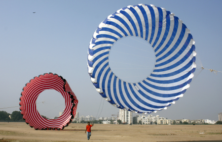 A kite-flying enthusiast tightens the strings of a 30 feet in diameter kite in Ahmedabad.