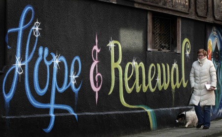 A woman walks past graffiti on the side of a building in Dublin.