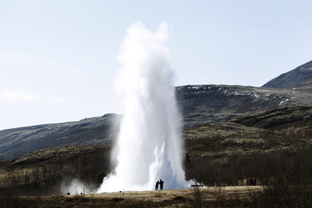 People look at a geyser in Geysir.