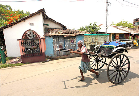 A handcart puller walks past the house of India's Railways Minister and Trinamool Congress (TMC) chief Mamata Banerjee in Kolkata.