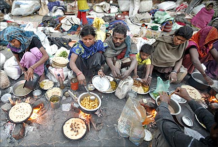 Homeless people prepare food on a roadside.